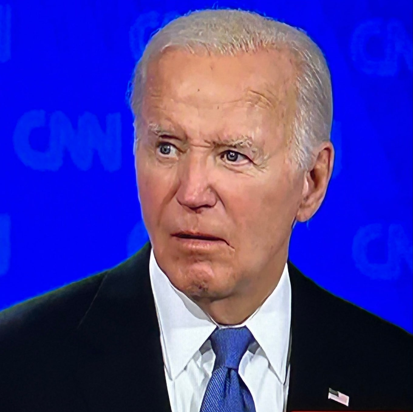 Joe Biden stands in front of a blue CNN debate background.